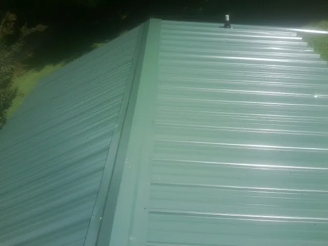 New green metal panels meeting at the ridge of a roof — Flat Roof Repair work by our crew in Round Top