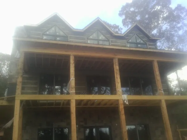 Dormers and porch framing on a large log home under construction — Roof Coating work by our crew in Round Top