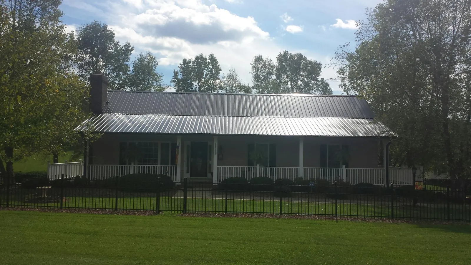 Gray metal roof on a brick ranch with a full width front porch — Gutter Guard Installation work by our crew in Round Top