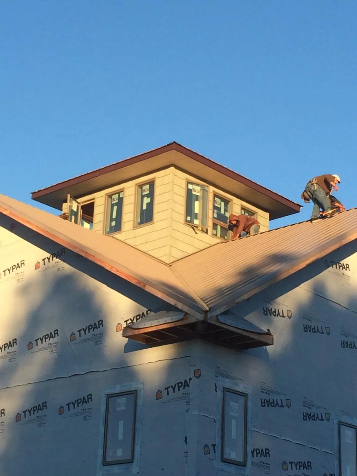 Roofers working around a rooftop cupola on a new metal roof at sunset — Roof Waterproofing in Round Top by Roofing Brothers